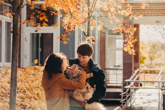 Young couple with a red cat on a background of an autumn city.