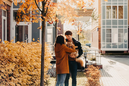Young couple with a red cat on a background of an autumn city.