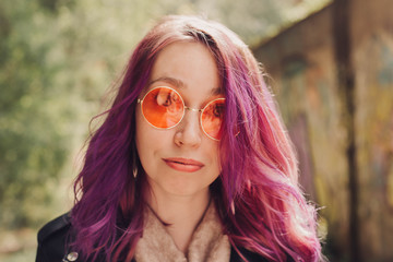 Woman in orange sunglasses and with colorful dyed hair.