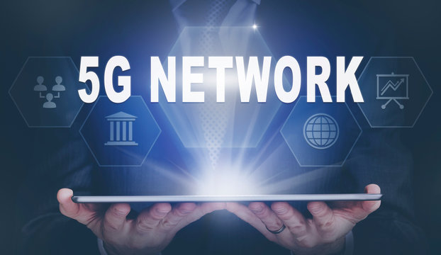 Businessman holding a computer tablet display projecting a 5G Network concept.