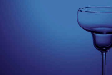 Empty wine glass on blue background. Back space.