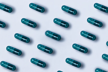  Pattern made with pharmaceutical green medicine pills, capsules on bright light background. Concepts of creative medicine. Minimal style pills isolated from the background. Medication background .