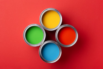 Cans of colorful paint on red background.