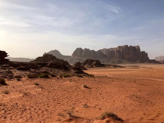golden desert with mountains in the back ground in Wadi Rum Jordan