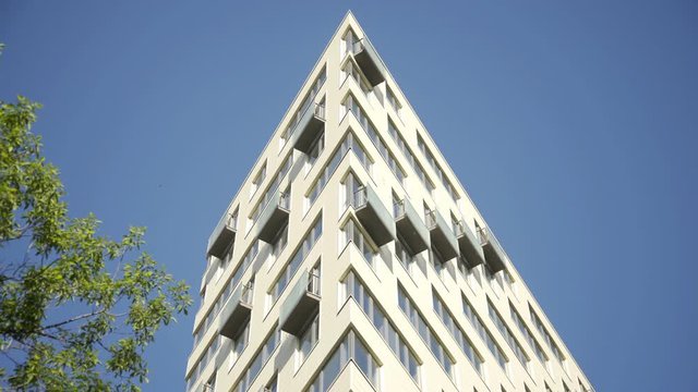 Exterior establishing shot of a apartment building. Residential building exterior with blue sky background. The building features exterior with small balconies