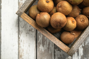 Ripe fresh kiwi fruits in wooden box on rustic background. Top view with  copy space.