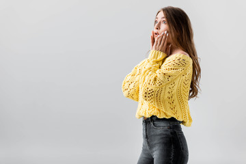 shocked girl looking away and touching face isolated on grey