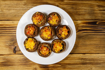 Baked mushrooms stuffed with minced meat, mushroom, paprika, onion and cheese on wooden table. Top view