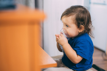 a little girl yourself holding the mask of the nebulizer, making inhalation