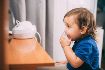 a little girl yourself holding the mask of the nebulizer, making inhalation