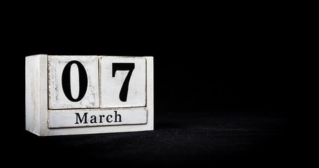 March 7th, Seventh of March, Day 7 of month March - white calendar blocks on black textured background with empty space for text.