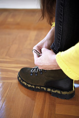 A girl tying a shoelace on her beautiful shoes.