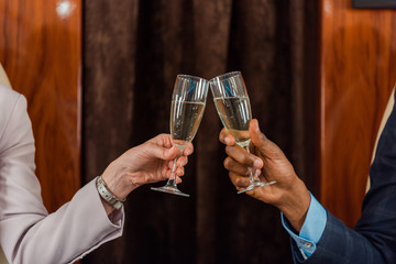 cropped view of african american man and woman clinking champagne glasses in private plane