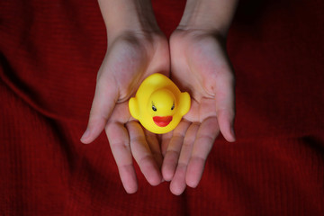 girl keep in hands small a yellow toy duck 