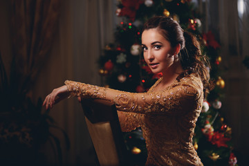 Beauty woman on new year background with lights bokeh in golden dress