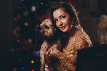 Beauty woman with dog on new year background with lights bokeh in golden dress