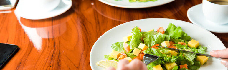 panoramic shot of woman holding cutlery near tasty salad in private jet