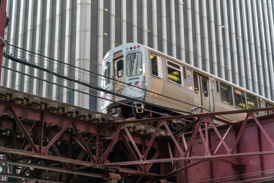 Day Time Establishing Shot Of Chicago L Train Passing By Downtown Office Building On Tracks Elevated Overhead Roadway.