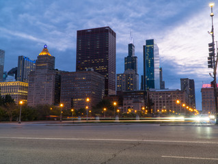 Fototapeta na wymiar Chicago skyline looking past a busy downtown road at night with car traffic light trails passing through intersection long exposure