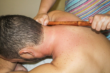 Young man receives a bamboo back massage.