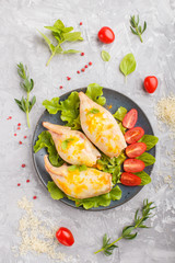 stuffed baked squid with greens on a blue ceramic plate on a gray concrete background, top view.