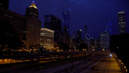 Night time establishing shot view of Chicago skyline over a large train yard junction transportation hub for railroad