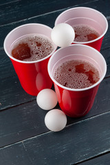 Wooden table with red cups and ball for beer pong