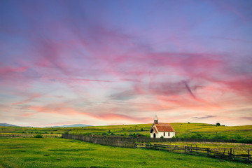 Beautiful sunset on a farm with a small catholic church.