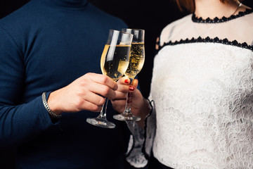 Girl and man on a black background with glasses of champagne