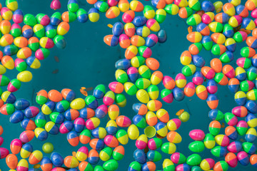 A multicolored plastic ball floated in the water with leaves falling from above.