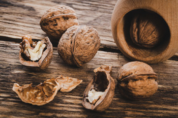 Group of walnut grains and whole walnuts with nutcracker on a wooden rustic table (vintage effect)