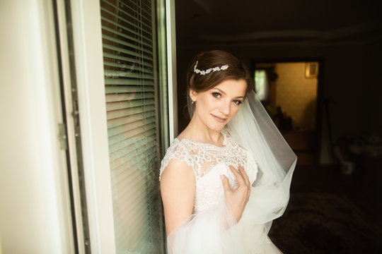 Beautiful bride style. Wedding girl stand in luxury wedding dress near window