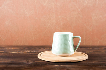 Clay cup on a wooden board on a dark background.