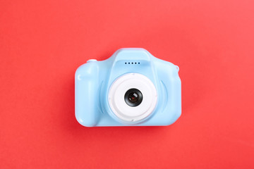 Light blue toy camera on red background, top view