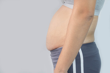Close-up side view of woman excessive belly fat isolated on gray background. Woman fat belly....