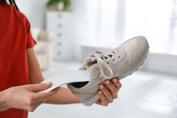 Woman putting orthopedic insole into shoe at home, closeup