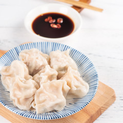 Fresh, delicious boiled pork gyoza dumplings, jiaozi on white background with soy sauce and...
