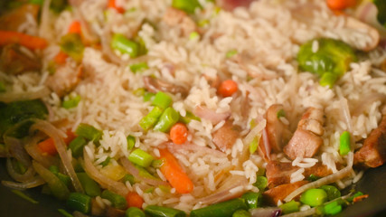 Cooking rice with meat and vegetables, closeup. Culinary background, gastronomy, Asian and Oriental cuisine. Thailand