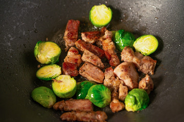 Frying meat with vegetables, on a black wooden background. Culinary, gastronomy