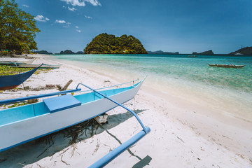 El Nido, Palawan, Philippines. White banca boat at Las cabanas beach with tropical island in background. Beautiful landscape scenery