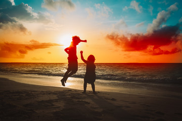 Fototapeta na wymiar kids have fun, boy and girl jump at sunset beach