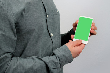 man holds in his hands a modern phone with green screen in an upright position with a slope, technology concept, close-up, copy space