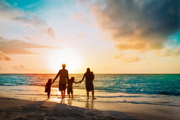 happy family with tree kids walk at sunset beach