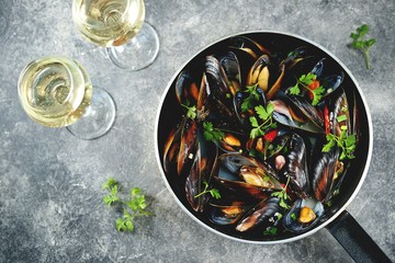 Fresh wild mussels in shells with green onions, garlic, parsley, chili pepper, white wine and olive oil. Top view. 