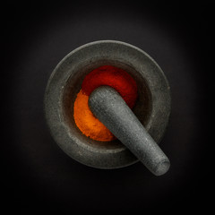 Fototapeta na wymiar Plan view of pestle & mortar and ground spices, shot on a dark background, with copy space