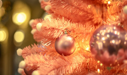 Fototapeta na wymiar Christmas tree with gold bauble ornaments. Decorated Christmas tree closeup. Balls and illuminated garland with flashlights. New Year baubles macro photo with bokeh. Winter holiday light decoration