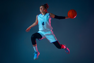 Target. Young caucasian female basketball player on blue studio background in neon light, motion...