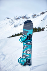 snowboard stuck in snow on a background of snowy mountains