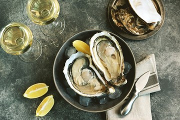 Giant fresh uncooked oysters in a shell with lemon on ice. Healthly food.