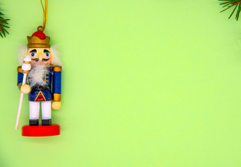 Fir branches and Christmas toy Nutcracker on a delicate green background.